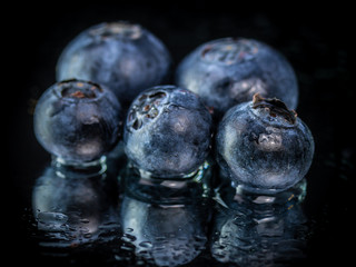 Fresh Blueberry fruit with water on a mirror , isolated on a black background
