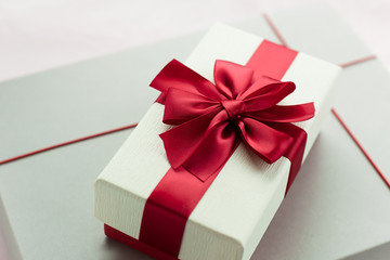 Gift box/ present with red bow on white/pink background. Festive backdrop for holidays: Birthday, Valentines day, Christmas, New Year. Flat lay