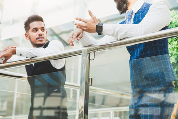 young business people are standing and talking on the background of glass offices. Corporate businessteam and manager in a meeting.