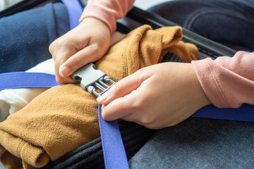 Happy young woman hands packing clothes into travel luggage on bed at home or hotel room for a new journey.  Tourism and vacation concept