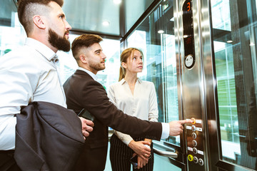 Business team group going on elevator. Business people in a large glass elevator in a modern...