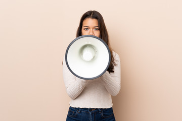 Young Colombian girl over isolated background shouting through a megaphone