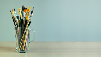 Paint brushes are in a glass jug on the table. Desktop wallpaper
