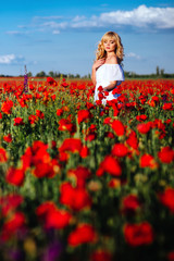 Naklejka na ściany i meble cheerful girl with curly blond hair in a huge poppy field alone, springtime, sunset