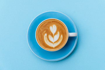 Cup of fresh coffee on blue background, top view