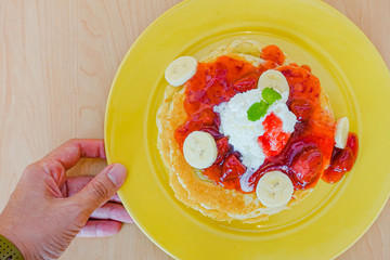 Pancakes served with banana, strawberry, strawberry jam and whipped cream