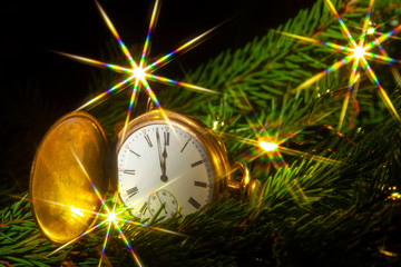 Close-Up Of Pocket Watch On Christmas Tree and the sparks of the Christmas garland. Five minutes to twelve-soon the new year!