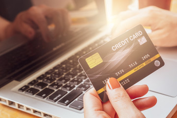 Close up of someone hand holding credit card during using laptop for online shopping. Online shopping is the process of buying goods and services from merchants over the Internet.