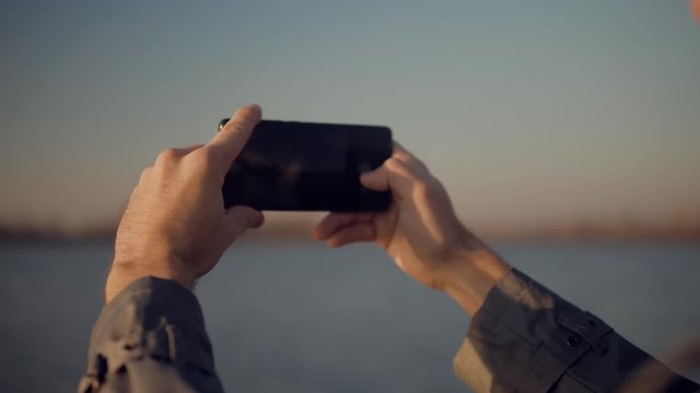 Mobile Photo.Picture On Smartphone.Man Taking Mobile Photo.Man Holding Mobile Phone Taking Picture At Sunset.Close Up Attractive Male Happy Using Mobile App For Photo Or Video.