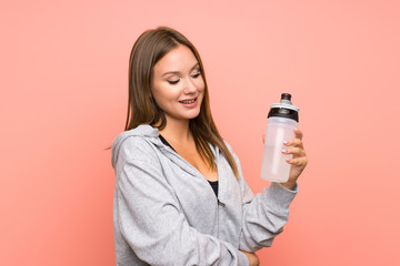 Teenager sport girl with a bottle of water over isolated pink background