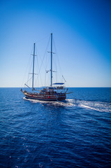 Fototapeta na wymiar The ship sails on a calm sea, in the background a cloudless sky