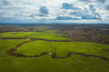 Green fields and rivers under a picturesque sky with clouds. Autumn landscape from above view