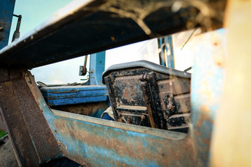 Shallow focus of an old dairy farm tractor interior showing the plastic bucket type drivers seat. Taken from the rear tractor window used for the driving checking the PTO.