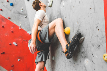 Sportsman climber moving up on steep rock, climbing on artificial wall indoors. Extreme sports and...