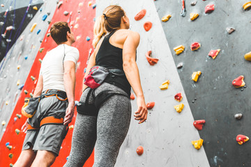 couple of athletes climber stand and watch on steep rock, climbing on artificial wall indoors. Extreme sports and bouldering concept. © xartproduction