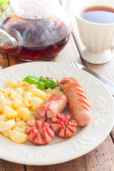 Fried sausages with pasta on a wooden plate on a wooden table, selective focus