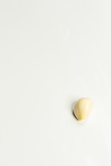 Peeled one garlic clove on a white background.