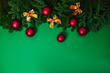 Natural green fir branches flat lay with red christmas balls and golden baws. Christmas card with copy space.