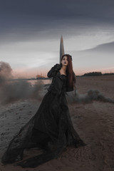 beautiful girl with smoke in hand and in a black dress stands on the shore of the Gulf of Finland in the 300th anniversary park in St. Petersburg