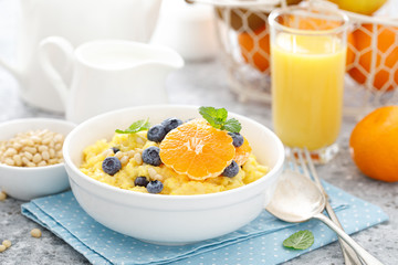 Corn porridge with fresh blueberry, orange and pine nuts in bowl served for breakfast