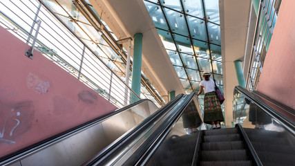 Asian woman riding up escalator in Metro station