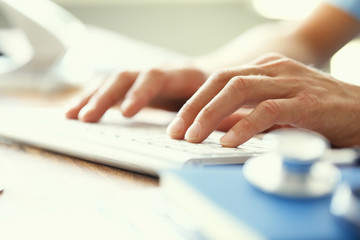 Medicine doctor's writing on keyboard in medical office close-up. Side view.
