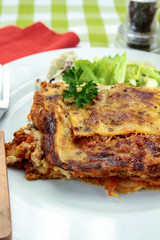lasagna with bolognese and green salad on a plate