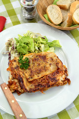 lasagna with bolognese and green salad on a plate