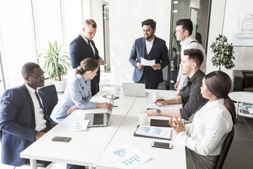 A team of young businessmen working and communicating together in an office. Corporate businessteam and manager in a meeting.