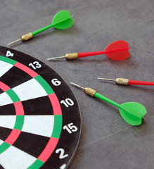 dartboard and dart arrows standing on black ground,
