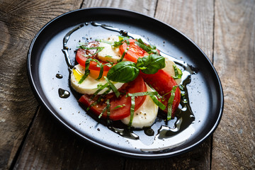Caprese salad on black plate on wooden table