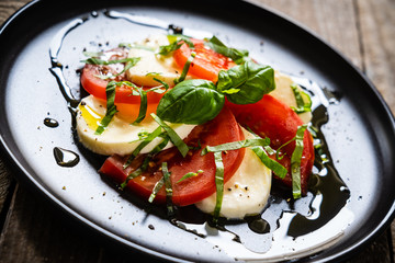 Caprese salad on black plate on wooden table