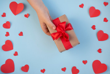 The Background Of Valentine's Day.Gift in hand, a Declaration of love, a box with a red ribbon on a light background. The Concept Of Valentine's Day. top view, copy space