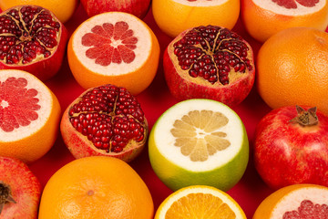 Grapefruit, orange, pomegranate, citrus sweetie on red background.