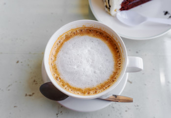 Latte coffee in a white cup on white table