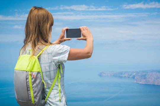 Girl hiker take a photo of distant cape
