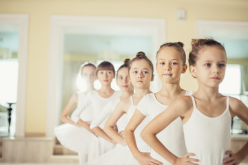 group of caucasian cute girls 7-8 years old dancing classic ballet together wearing white tutu...