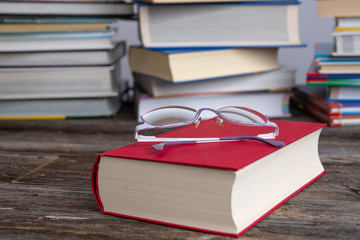 book and reading glasses in front of piles of different books