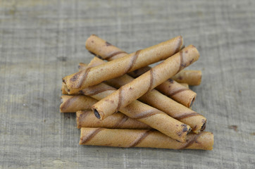 Chocolate waffle roll sticks on wooden background
