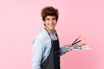 Young caucasian man over isolated pink background holding a palette