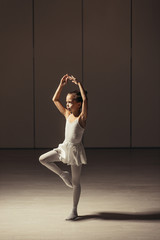 Fototapeta na wymiar graceful kid ballerina in white tutu skirt performing dance, dream about becoming great ballet dancer isolated in ballet studio