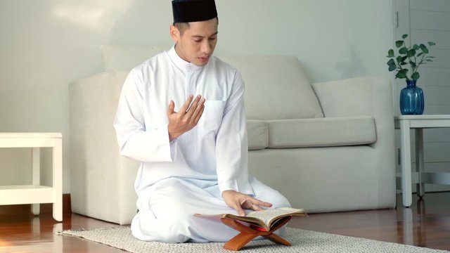 Portrait of an Asian Muslim man reciting surah al-Fatiha passage of the Qur'an, public item of all Muslims in a daily prayer at home in a single act of sujud called a sajdah or prostration