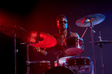 portrait of professional drummer man vigorous and expressive, emotional playing on drum set isolated in studio
