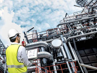 Engineer holding walkie talkie are working orders the oil and gas refinery plant. Industry...