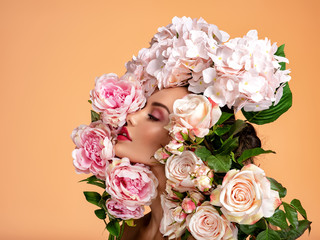 Beautiful white girl with flowers around face, profile portrait.  Attractive girl with big many flowers near face. Art portrait, Woman and flowers. Beauty treatments. Spa salon. Beauty salon.