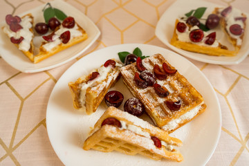 Belgian waffles with whipped cream and fresh ripe cherries