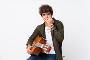 Young caucasian man with guitar over isolated white background nervous and scared