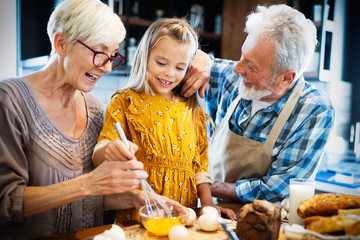 Happy grandparents with grandchildren making breakfast in kitchen