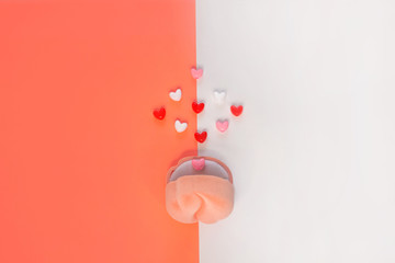 Pink velvet ring box on white and coral orange background with hearts top view. St. Valentines Day...