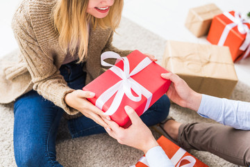 Christmas and holidays concept - Close-up of young happy couple opening gifts at home.